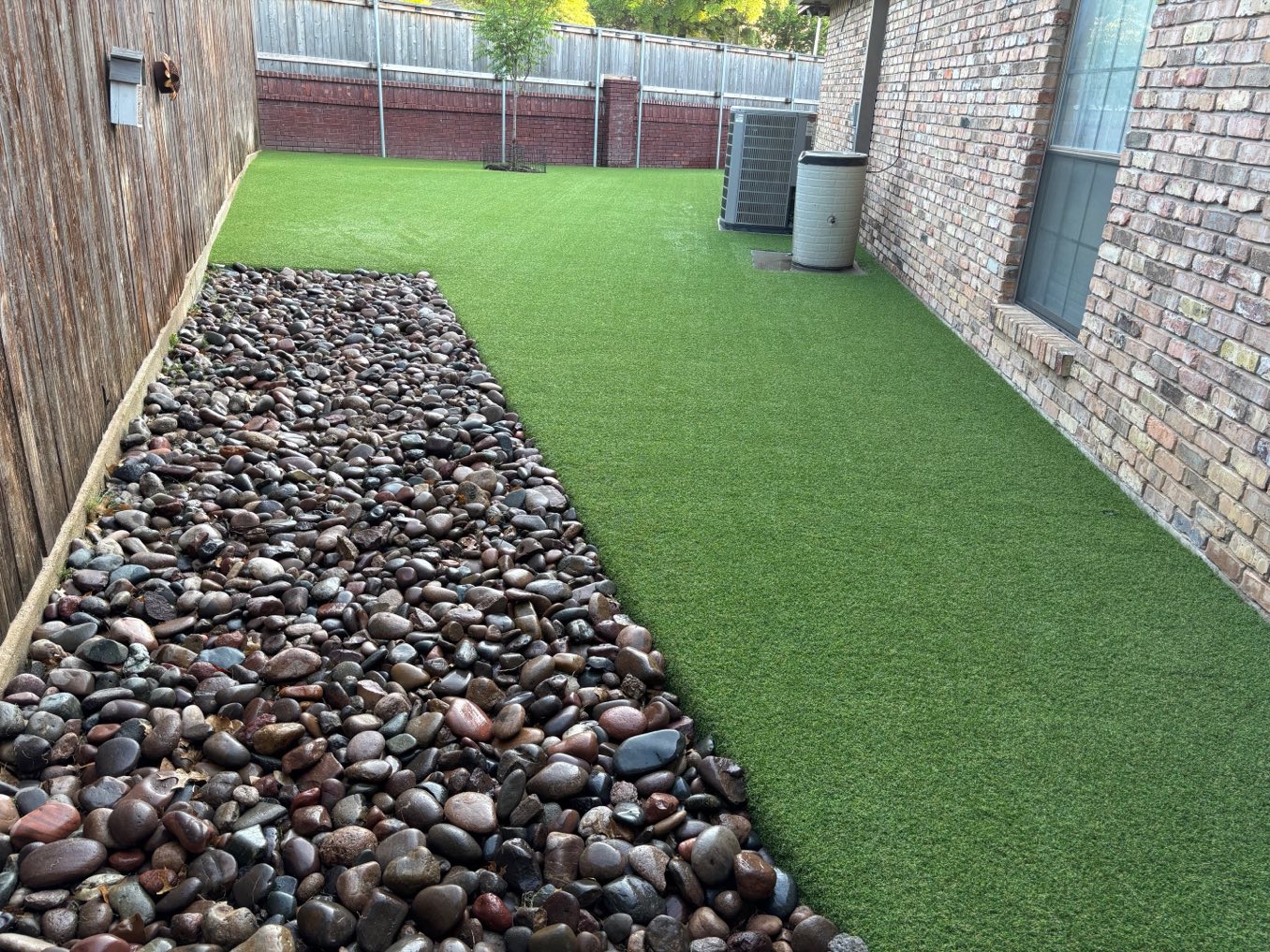 After: a narrow gravel-lined side yard against a brick wall