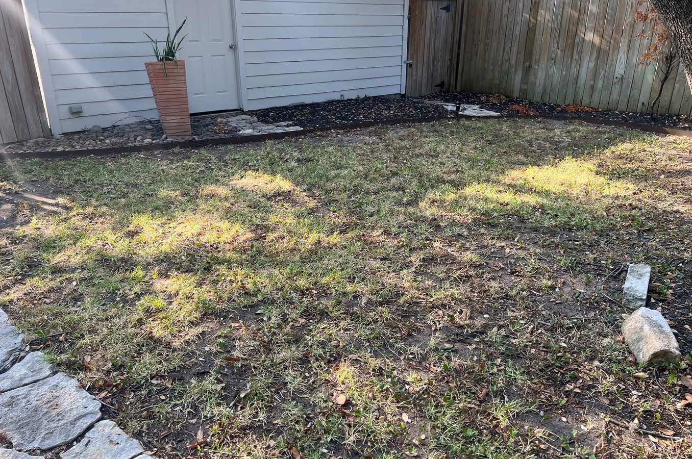Before: a patchy side lawn beside a garage