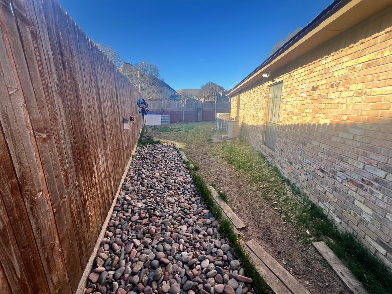 Before: a narrow gravel-lined side yard against a brick wall