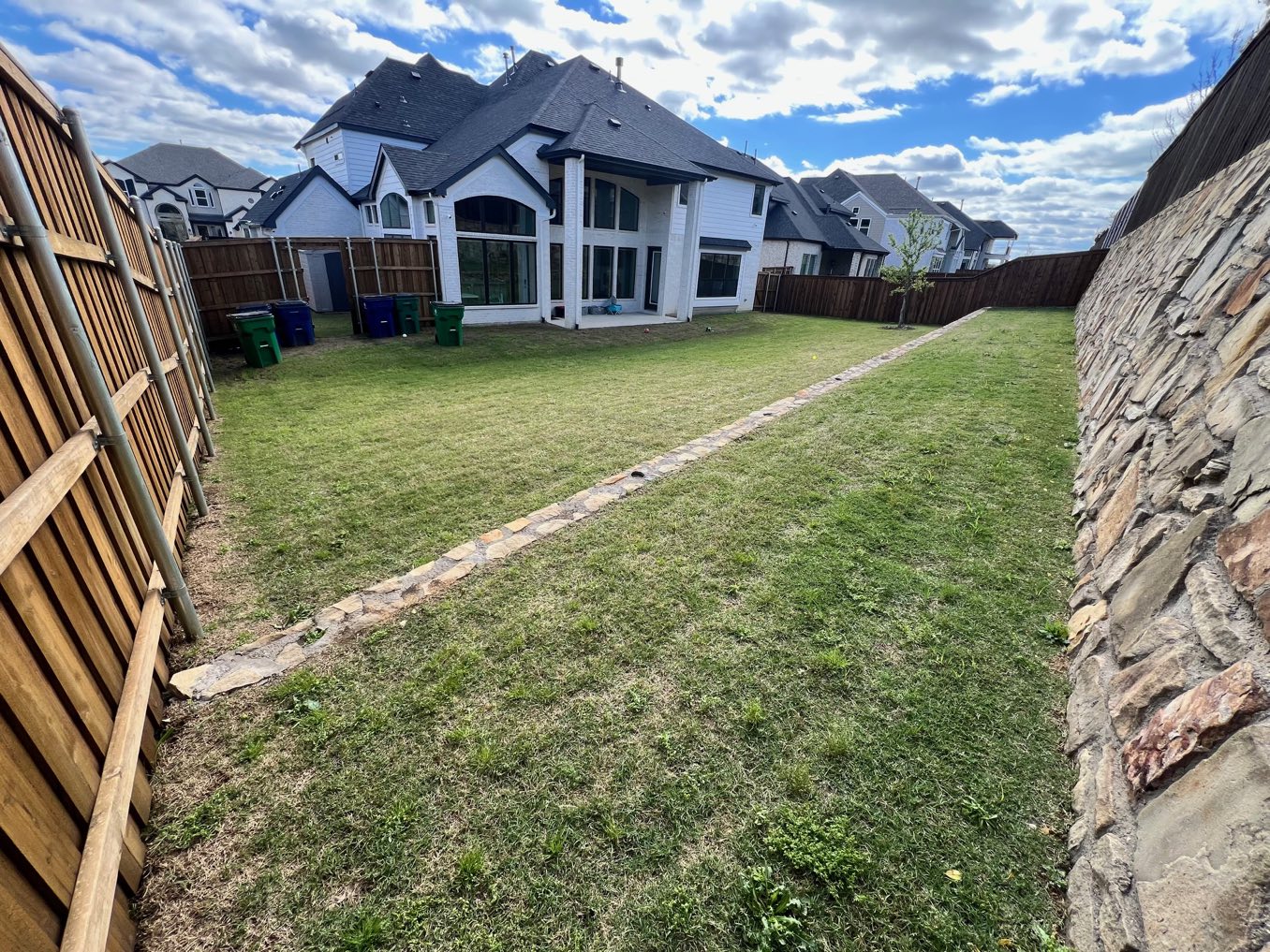 Before: a long backyard strip beside a stone retaining wall