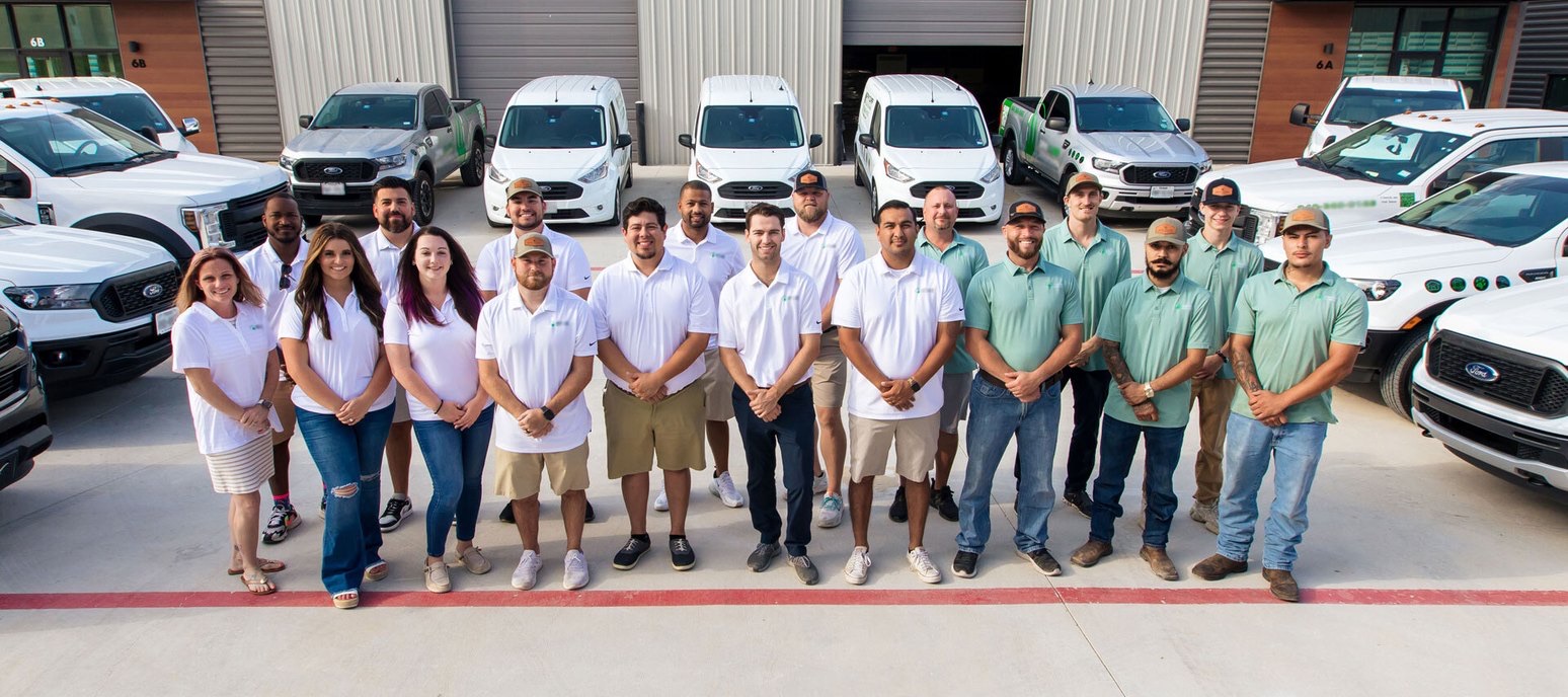 The Artificial Grass Pros install team standing in front of the company truck and van fleet